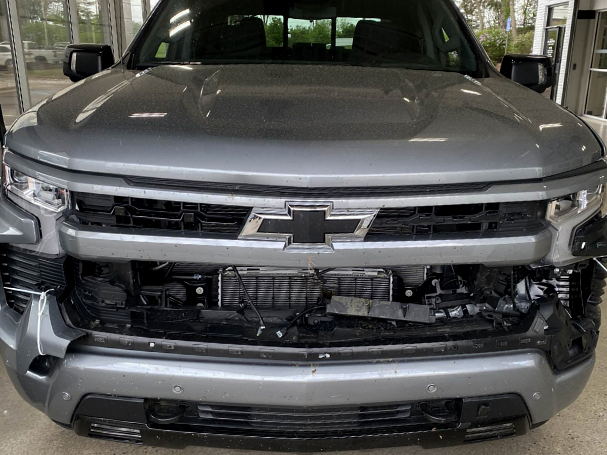 Chevrolet Silverado with front bumper removed and grille and radiator support exposed after a front-end collision, before repair at Al Serra Body Shop in Grand Blanc, MI