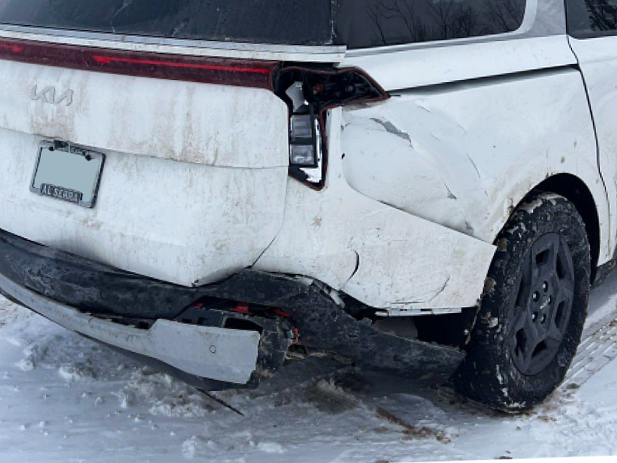 White Kia Carnival with crushed rear quarter panel and bumper damage before repair at Al Serra Body Shop in Grand Blanc, MI